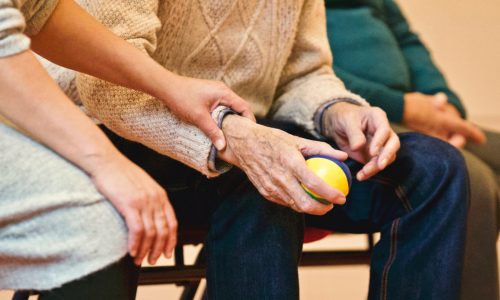 younger hand on arm of older man holding apple