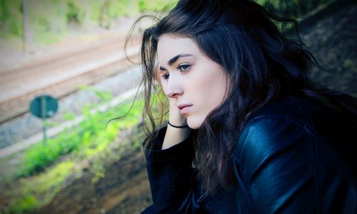 young woman looking thoughtful by window