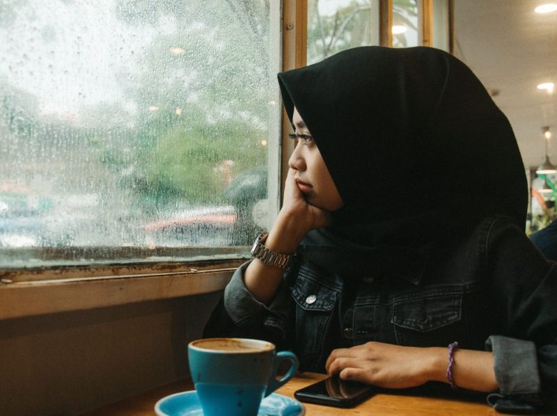 woman in headscarf looking out of window