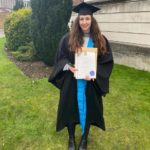 young woman in cap and gown holding degree certificate