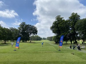 golfers blaying between Aaction for Carers Surrey flags