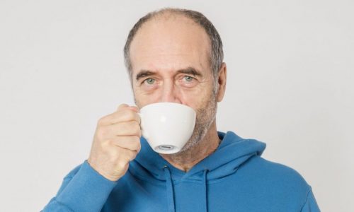 man in blue hoodie drinking cup of tea