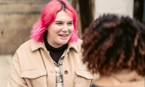 young woman with pink hair talking to young man