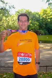 smiling man in orange tshirt with marathon medal