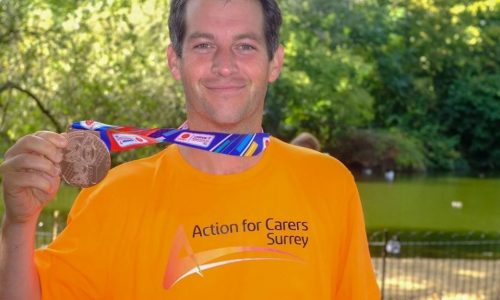 smiling man in orange tshirt with marathon medal