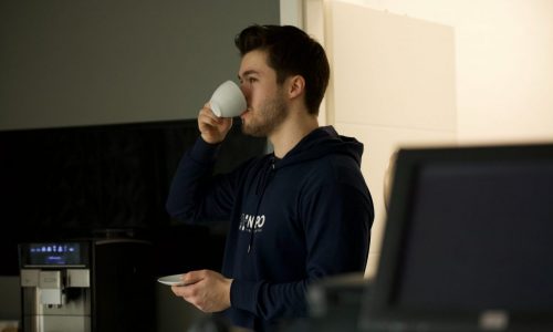 man in blue hoodie with cup