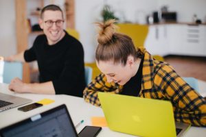 woman laughing with green laptop, man smiling