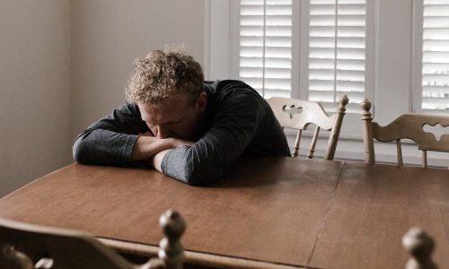 Man has head in hands at table