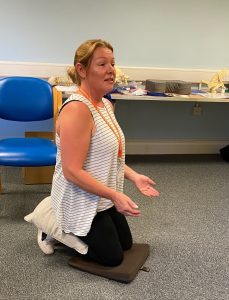 Woman kneeling on floor to demonstrate best posture
