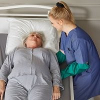 Carer using slide gloves to help a women lying in bed to move
