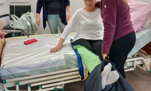 Person helping person move their legs on a bed