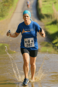 Women running in Action for Carers T-shirt, splashing through puddle.