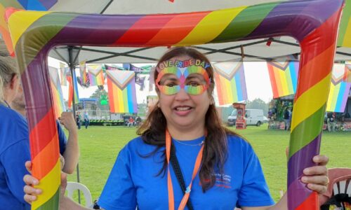 ACS Volunteer at PRIDE surrey with rainbows all around