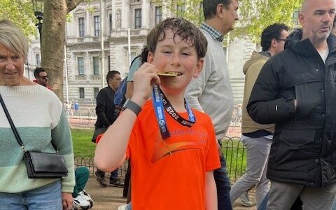 Ollie holding up his medal arefer running to raise funds for Action for carers