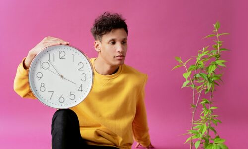 thoughtful man with clock on pink background