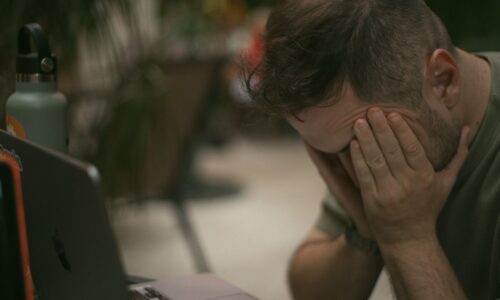 stressed carer holds head in his hands